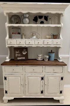 a white china cabinet with black counter top and flowers in vases on the shelf