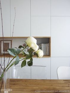 there is a vase with flowers in it on the table next to a book shelf