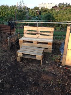 a wooden bench sitting in the middle of a field next to some plants and trees