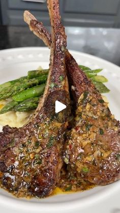 a white plate topped with meat and asparagus