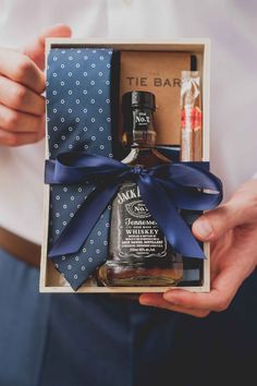 a man is holding a gift box with an alcohol bottle and two bottles in it