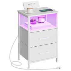 a white night stand with two drawers and a purple light