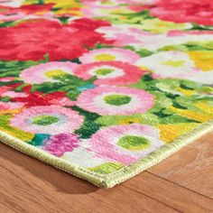 an area rug on the floor with flowers and leaves in pink, green, yellow, red