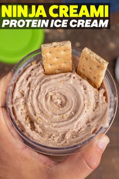 a hand holding a bowl filled with peanut butter and crackers on top of it