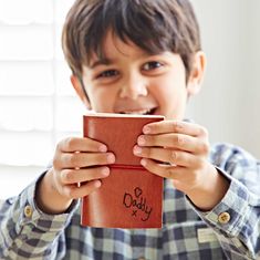 a young boy holding up a book with the word daddy written on it and smiling