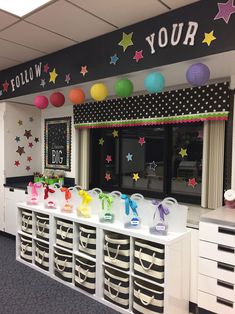 an office decorated with colorful paper lanterns and stars on the wall, along with baskets filled with toys