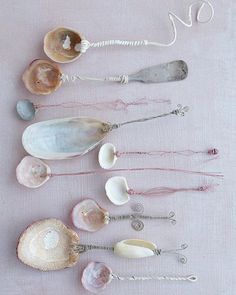 several seashells are arranged on a pink tablecloth with silver hooks and beads