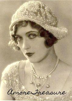 an old photo of a woman wearing a tiara and pearls on her head, looking at the camera