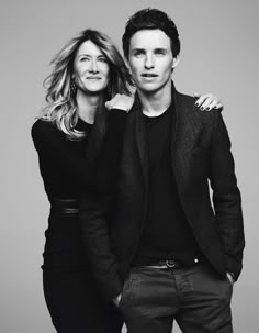 a man and woman standing next to each other in black and white, posing for the camera