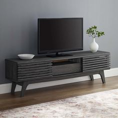 an entertainment center with a flat screen tv on it's stand in front of a gray wall