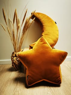 a star shaped pillow sitting on top of a wooden floor next to a pine cone