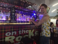 a man standing next to a bar filled with bottles