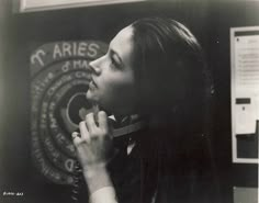 a black and white photo of a woman talking on a cell phone in front of a sign