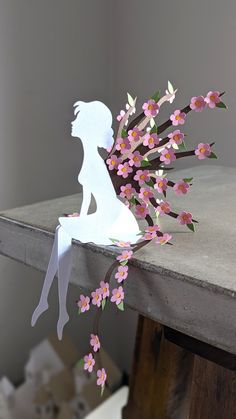 a paper cut out of a woman sitting on a table with flowers in her hair