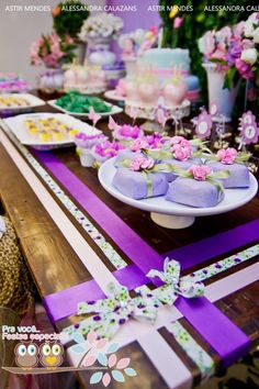 the table is decorated with purple and white ribbons, flowers, and cake on it