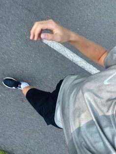 a skateboarder is holding his board while standing on the street with one hand in the air