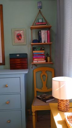 a room with a chair, bookshelf and lamp on the table in front of it