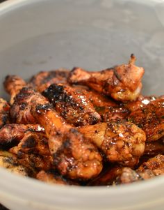 a white bowl filled with chicken wings covered in sauce