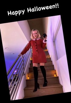 a woman in a red dress and black boots is standing on stairs with her arms out