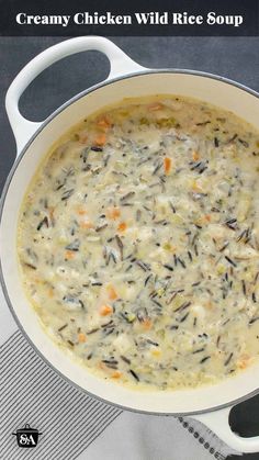 creamy chicken wild rice soup in a white bowl on a gray tablecloth with spoons