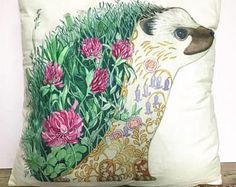 a pillow with an image of a bird and pink flowers on it sitting on a table