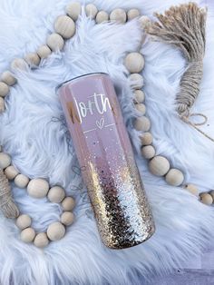 a pink and gold glitter tumbler sitting on top of a white fur covered floor