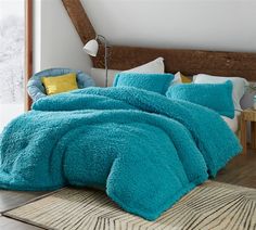 a bed covered in blue fluffy blankets and pillows