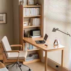 a desk with a laptop computer on top of it next to a chair and bookshelf