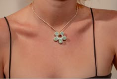 a woman wearing a necklace with three flowers on the front and two petals on the back