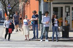 a group of people standing on the side of a street next to a traffic light