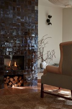 a living room with a fire place and a chair in front of the fireplace that is lit