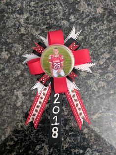 a red and white award ribbon with a photo in the center on top of it