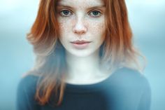 a woman with freckles on her face and red hair is looking at the camera