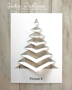 an origami christmas tree made out of white paper on a wooden background with text overlay