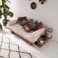 a living room with white walls and lots of pillows on the back of the couch