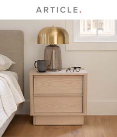 a nightstand with glasses on it next to a bed