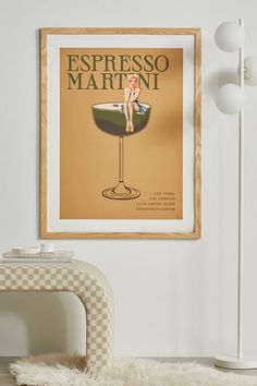 a poster hangs on the wall above a chair and table with a vase in front of it