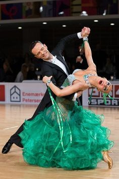 a man and woman dancing on a dance floor with their hands in the air while holding onto each other's strings