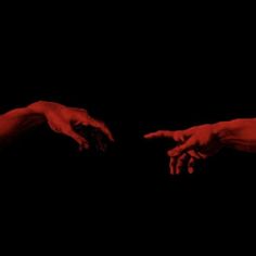 two hands reaching towards each other with red paint on their fingertipss in the dark