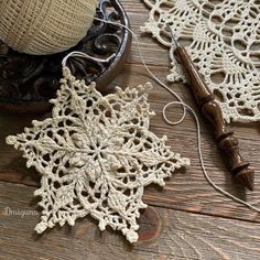 crocheted snowflake ornament on wooden table next to ball of yarn