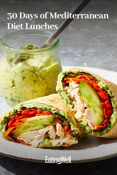 a sandwich cut in half on a plate next to a jar of guacamole