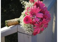 a bouquet of pink flowers sitting on top of a white fence