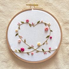 a heart - shaped frame with flowers and leaves in the shape of a cross stitch