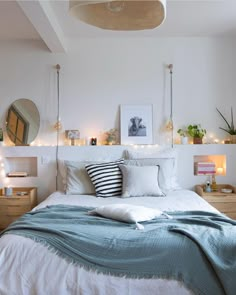 a bed with white sheets and pillows on top of it next to some lights in the corner