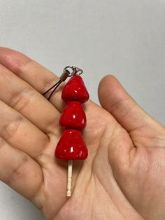 a person is holding three red candy lollipops on a stick in their hand