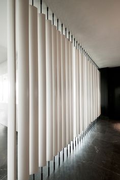 an empty room with white vertical blinds on the wall and black flooring in front of it