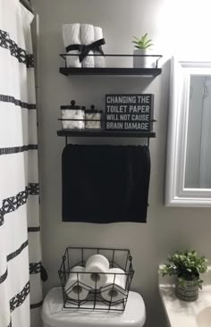 a white toilet sitting next to a sink in a bathroom with black and white decor