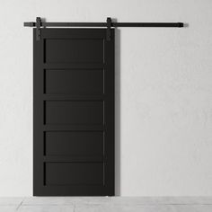 an open black barn door in front of a white wall with two bars on it