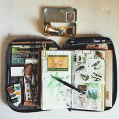 an open travel bag with various items in it, including pens and inkwells