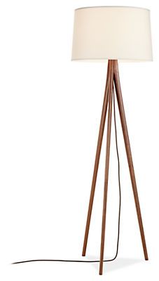 a wooden tripod floor lamp with a white shade on the top and a black cord attached to it